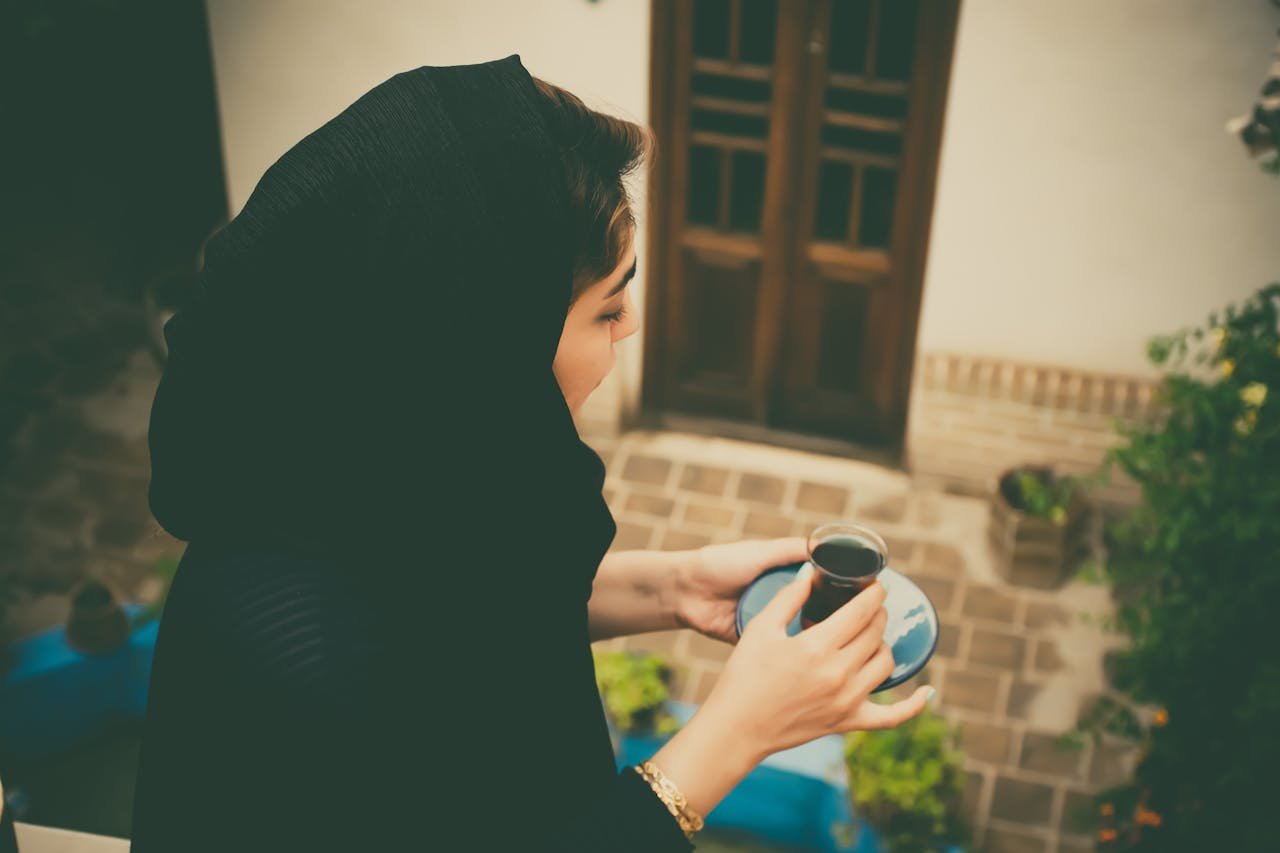 An Iranian woman savoring tea in a traditional courtyard in Kashan, Iran.