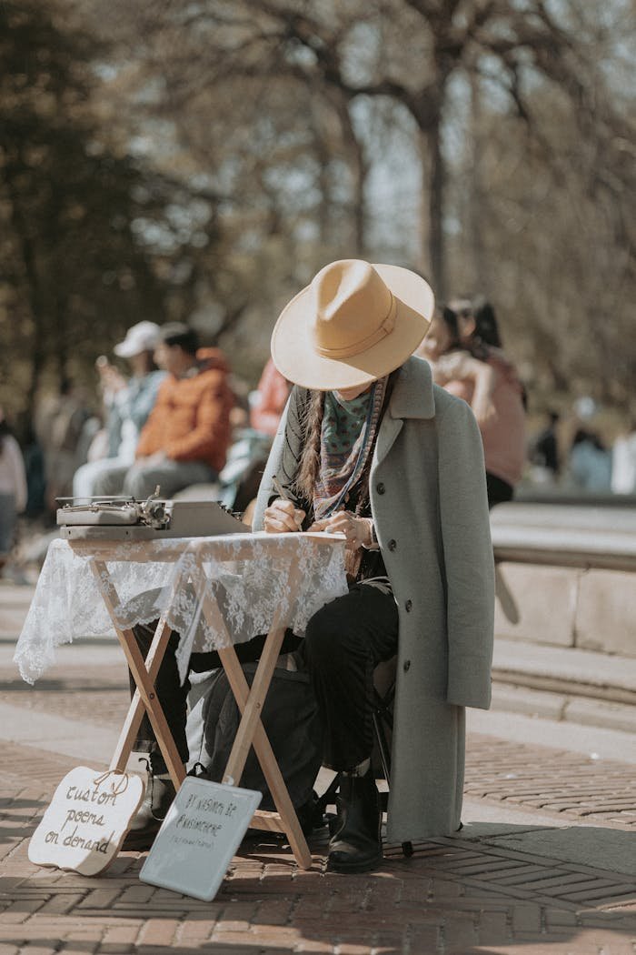 who-we-are-01 A person in an overcoat and hat writes on a typewriter at an outdoor street location.
