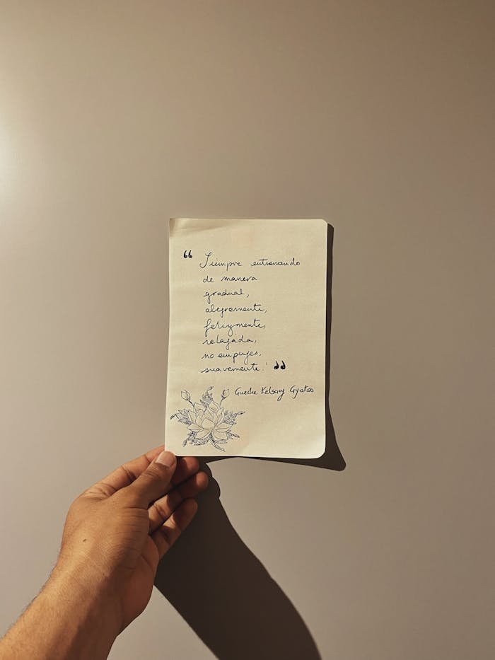 who-we-are-03 A hand holds a handwritten note with a poem on a neutral background, creating a simple and intimate scene.